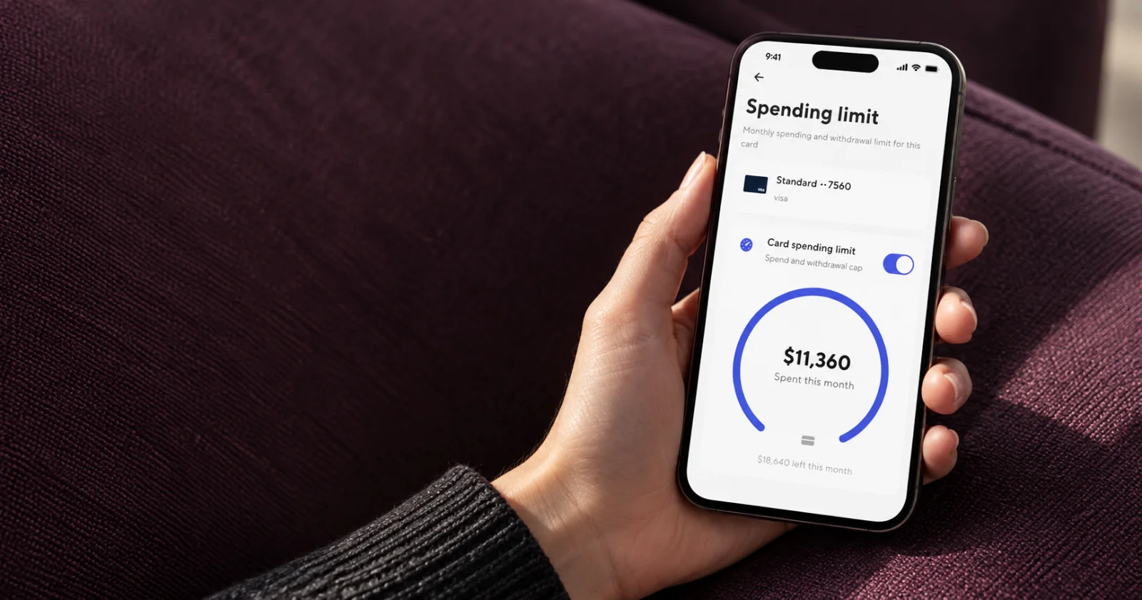 A person viewing an enabled card spending limit in Dara against plum upholstery.